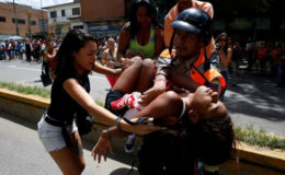 A police officer carries a woman who fainted while gathering to try to buy pasta outside a supermarket in Caracas, Venezuela, June 10, 2016. REUTERS/Carlos Garcia Rawlins/File Photo