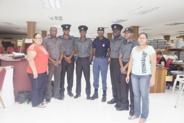 Five of the six firemen who were injured as a result of the Gafoors fire pose with representatives of the company, including Finance Director Michael Daniels (second left) shortly after receiving their cheques. 
