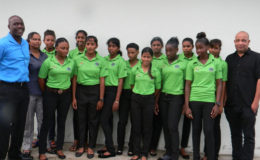 Members of the Guyana U-19 girls team pose for a photograph with Chief Executive Officer of Top Brandz Distributors, Wayne James (right) and Technical Development Officer of the Guyana Cricket Board, Colin Stuart (left) manager, Devika Gobin (2nd left). Captain Plaffianna Millington  is first from left front row).