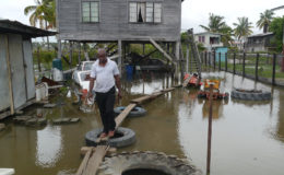 Glendon Blair, a mechanic, walking on his makeshift bridge in his flooded yard