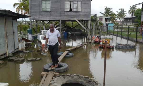 Glendon Blair, a mechanic, walking on his makeshift bridge in his flooded yard