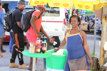 Maylene Innis with her water cooler selling at the junction of Regent and Wellington streets (Photo by Keno George) 
