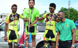 Geron Williams pops a bottle of champagne on the podium with second place finisher, Raynauth Jeffrey (right) and Stephano Husbands both of Team Coco’s. (Orlando Charles)