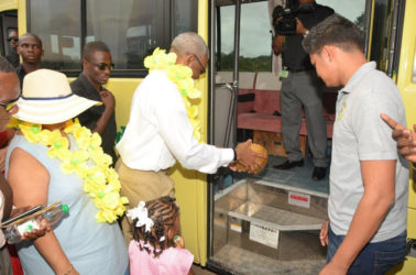President David Granger pours coconut water to officially commission the 30-seater bus, while Minister of Social Cohesion, Amna Ally looks on. Sajid Baksh, a representative of the donor, Suresh Jagmohan is at right. (Ministry of the Presidency photo)  