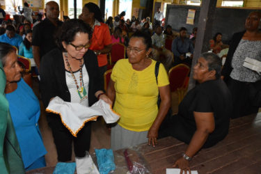 Two participants in the Self Reliance and Success in Business Workshop in Mahdia give First Lady,  Sandra Granger (centre) a closer look at their hand-embroidered tea towels.  (Ministry of the Presidency photo)