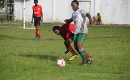 Ryan Hackett of Chase Academy (white/right) trying to maintain possession of the ball while being challenged by an opposing player during his team’s opening fixture in the Digicel Schools Football Championship at the Ministry of Education ground yesterday.
