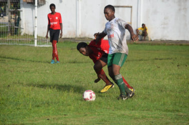 Ryan Hackett of Chase Academy (white/right) trying to maintain possession of the ball while being challenged by an opposing player during his team’s opening fixture in the Digicel Schools Football Championship at the Ministry of Education ground yesterday. 