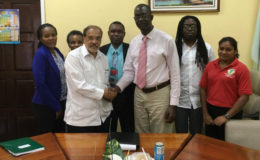 Trevor Benn (right), Commissioner of Guyana Lands and Surveys in a symbolic handshake with Dr. John Ronald Ford, Sub-regional Coordinator, FAO Sub-regional Office for the Caribbean. (Ministry of the Presidency photo)