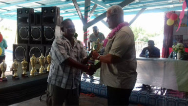  A fisherman (left) receives his award from Minister of Agriculture Noel Holder yesterday 
