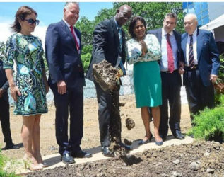 Prime Minister Keith Rowley attended by assorted dignitaries doing sod-turning duties at the site of the planned car park.