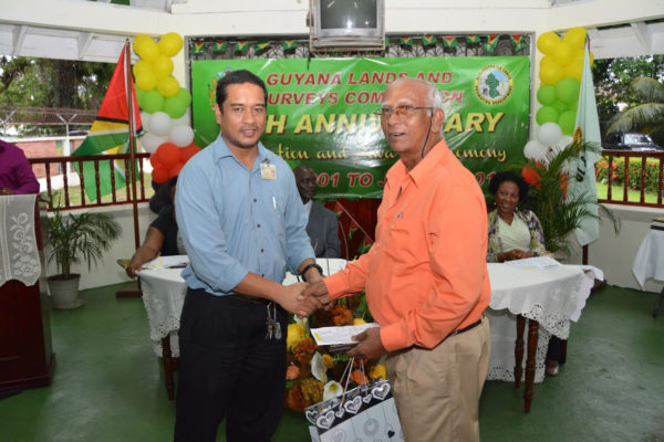Land Information and Mapping Manager, Naseem Nasir (left) presenting a special award to Mr. Abdul Khan who will be proceeding into retirement after serving the Commission for 15 years. (Ministry of the Presidency photo)
