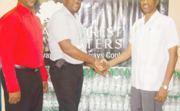Dr. Douglas Slater Assistant Secretary General of Human and Social Development of Caricom Secretariat receive the donation from RainForest Water Brand Manager Clive Pellew while Sherwin-Toyne-Stephenson of the CARICOM Secretariat looks on.
