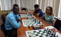 Sheriffa Ali (right) smiles as she opposes Frankie Farley during their game at the Andrew Arts Memorial Chess Tournament last Sunday at the National Resource Centre. Ali is a member of the 2016 Olympiad chess team which represents Guyana in Azerbaijan in September. She has been playing competitively for the past decade, and should do well at the Olympiad. On her right is her brother Saeed Ali. (Photo by Ryan Singh)