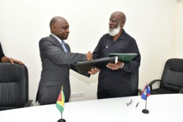 Guyana Foreign Affairs Minister, Carl Greenidge (left) exchanges a signed agreement on trade and other matters with Belize Foreign Affairs Minister, Wilfred Elrington (GINA photo)