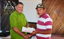 Minister of Indigenous Peoples’ Affairs, Sydney Allicock (left)  handing over a cheque to a toshao of one of the beneficiary villages
