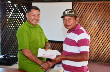Minister of Indigenous Peoples’ Affairs, Sydney Allicock (left)  handing over a cheque to a toshao of one of the beneficiary villages 