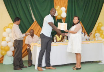 Ronald Austin of the Office of the Presidential Advisor on Youth Empowerment presents a certificate to Ulita Henry (GINA photo)