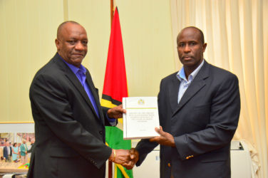  Minister of State Joseph Harmon receiving the report from Brigadier (Rtd) Bruce Lovell at the Ministry of the Presidency (Ministry of the Presidency photo) 