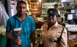 Jonathan Sunich, Canada-born son of Ramesh Sunich CEO of the Trophy Stall and Inspector Cynthia Kelly, Chairperson of the Guyana Association of Police Women display the champion trophies for Sunday’s Rising Sun Turf Club meet on Sunday.