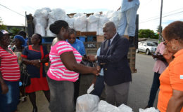 Minister of Citizenship, Winston Felix (right) presents a parcel to one recipient at the Community Development Centre at Union Village. (Ministry of the Presidency photo)