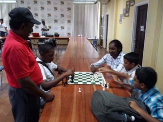 Students of St Stanislaus College kibitzing (playing chess for fun) on a cloudy Sunday afternoon at the National Resource Centre during the recent Andrew Arts Memorial chess tournament. The students on the right are: Ghansham Alijohn, John Wong and Jessica Callendar. On the left, playing the black pieces, is Jaden Taylor. Standing next to him is senior member of the Guyana Chess Federation David Khan.