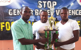 Captains of  Tucville Delon Williams (left) and North East La Penitence Michael Payne (right) posing with the Ministry of Education/Petra Organization Soft Shoe Championship trophy ahead of their finale while Tournament Coordinator Troy Mendonca (centre) looks on