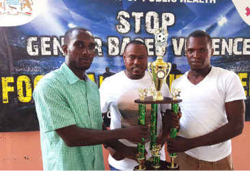 Captains of  Tucville Delon Williams (left) and North East La Penitence Michael Payne (right) posing with the Ministry of Education/Petra Organization Soft Shoe Championship trophy ahead of their finale while Tournament Coordinator Troy Mendonca (centre) looks on 