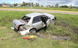 The state of the vehicle yesterday after the accident. Damage can be seen to the rear of the car and the front bumper, as well as the back windscreen and front right-side window, which both have the glass missing. The contents of the trunk can also be seen lying nearby in the grass. (Photo by Keno George)