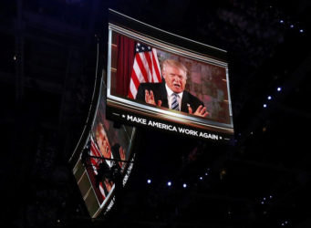 U.S. Republican Presidential Nominee Donald Trump is shown on video monitors as he speaks live to the crowd from New York at the Republican National Convention in Cleve-land, Ohio, U.S. July 19, 2016. REUTERS/Mario Anzuoni