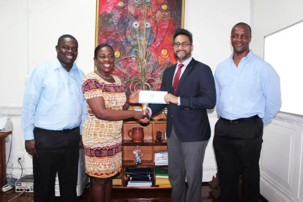 Managing Director of Republic Bank, Richard Sammy (second from right) handing over the cheque to Minister within the Ministry of Education,  Nicolette Henry.
