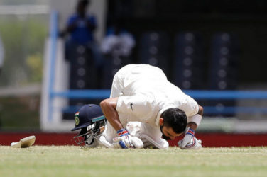 India captain Virat Kohli celebrates his maiden double century by kissing the turf at the Vivian Richards Cricket Ground. (Photo courtesy WICB)