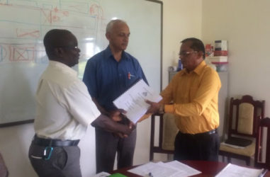 Minister of Communities Ronald Bulkan (centre) looks on as Permanent Secretary Emil McGarrell (left) hands over the contract to Managing Director of Puran Brothers Disposal Inc. Lakenauth Puran after it was signed.