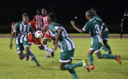 Omar Brewley (left) of Wismar/Christianburg in the process of receiving a pass while being pursued by several players from Sir Leon Lessons during their semi-final fixture at the Leonora Sports Facility in the Digicel Schools Football Championship.
