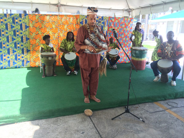 Bishop Andre Irving (centre) performing a libation and African prayer accompanied by drumming performed by the Buxton Fusion Group (background) during the Ministry of Education, Department of Culture, Youth and Sport’s launching of Emancipation celebrations yesterday.  (Dhanash Ramroop photo) 