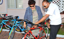 Deavindra Jagroo showing Minister of Social Cohesion, Amna Ally one of the bikes. (Ministry of the Presidency photo)