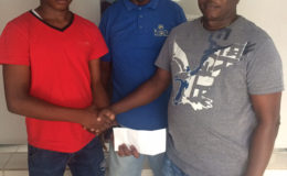 Juvenile cycle champion Zaman Khan’s (left) sojourn to the Junior Caribbean Cycling Championships was made possible by Steven Edwards (right). Coach of the team Randolph Roberts is pictured at centre. 