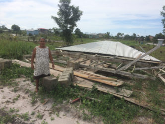 Herman Williams standing next to her sister’s half-finished house that was leveled by the storm. 