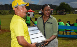 Minister within the Ministry of Education,  Nicolette Henry handing over the floodlights to a member of the District Sports Council. (Ministry of the Presidency photo)