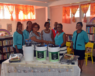 Secretary of the Retrieve CDC Ann Ramsey (right) hands over the paint to branch librarian Annis Craig as other members of staff look on.