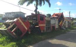 The derelict fire trucks parked on the side of the road. 
