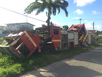 The derelict fire trucks parked on the side of the road. 