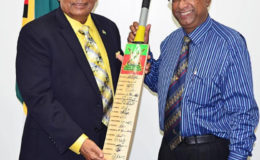 Prime Minister Moses Nagamootoo (left) collects an autographed Guyana Amazon Warriors bat from team Manager Omar Khan