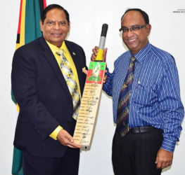 Prime Minister Moses Nagamootoo (left) collects an autographed Guyana Amazon Warriors bat from team Manager Omar Khan