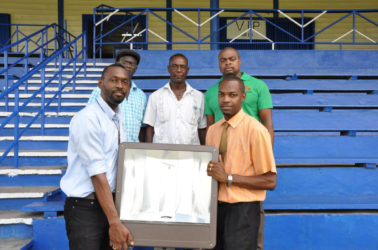 Director of Sport, Christopher Jones (left) hands over one of 15 floodlamps that will be erected at the MSC Ground to Regional Executive Officer, Region 10, Gavin Clarke yesterday.