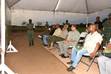 President David Granger (seated fourth from left) pays keen attention as Deputy Chief-of-Staff of the Guyana Defence Force Colonel George Lewis explains the elements of exercise ‘Homeguard.’ Minister of Foreign Affairs Carl Greenidge (seated at right), Prime Minister Moses Nagamootoo (seated second from right) and Minister of State Joseph Harmon (seated third from left) also look on. (Ministry of the Presidency photo)