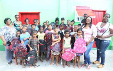 A group of children from Joshua House who received donations of backpacks and stationery from the Guyana Goldfields’ Women in Mining Group. In photo are: Gladys Accra, Administrator of the Joshua House Orphanage (left), Maya Layne (second, left), Trudy Ferrier (third, left), Nichola Scott (right) and Marisa Hohenkirk (second, right) of the Women in Mining Group. 