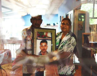 Krisha Sieunarine and wife Flora holding a photograph of their only son who was killed during a fight with Krishna four months ago.