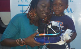 Cultural Ambassador of Give Another Chance Foundation, Melissa “Vanilla” Roberts handing over footwear and backpack to a child.