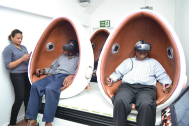 Two of the older patrons enjoying the virtual reality machine during Tuesday’s launch of the Universal Games Guyana Arcade at the Giftland Mall. 