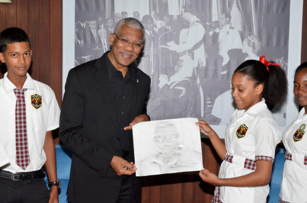 Hannah Monroe hands over the portrait she drew with charcoal to President David Granger, earlier today at the Ministry of the Presidency. (Ministry of the Presidency photo)